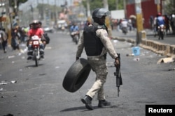 Un oficial de la Policía Nacional de Haití saca un neumático de una barricada en una calle de Puerto Príncipe, Haití, el 8 de julio de 2018. REUTERS / Andres Martinez Casares.