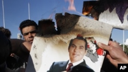 In this Jan. 24, 2011 picture, protestors burn a photo of former Tunisian President Zine El Abidine Ben Ali during a demonstration against holdovers from Ben Ali's regime in the interim government in Tunis, Tunisia.