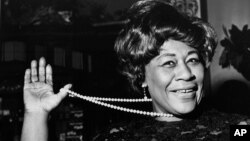 FILE - In this Feb. 22, 1968 file photo, American jazz singer Ella Fitzgerald swings her necklace as she arrives at the Carlton Theatre in London, England. The National Portrait Gallery is putting up a photograph of Fitzgerald, often referred to as "The First Lady of Song." The portrait is on view beginning Thursday, April 13, 2017, ahead of the 100th anniversary of Fitzgerald's birth. Fitzgerald, who died in 1996 at the age of 79, would have celebrated her 100th birthday April 25. 