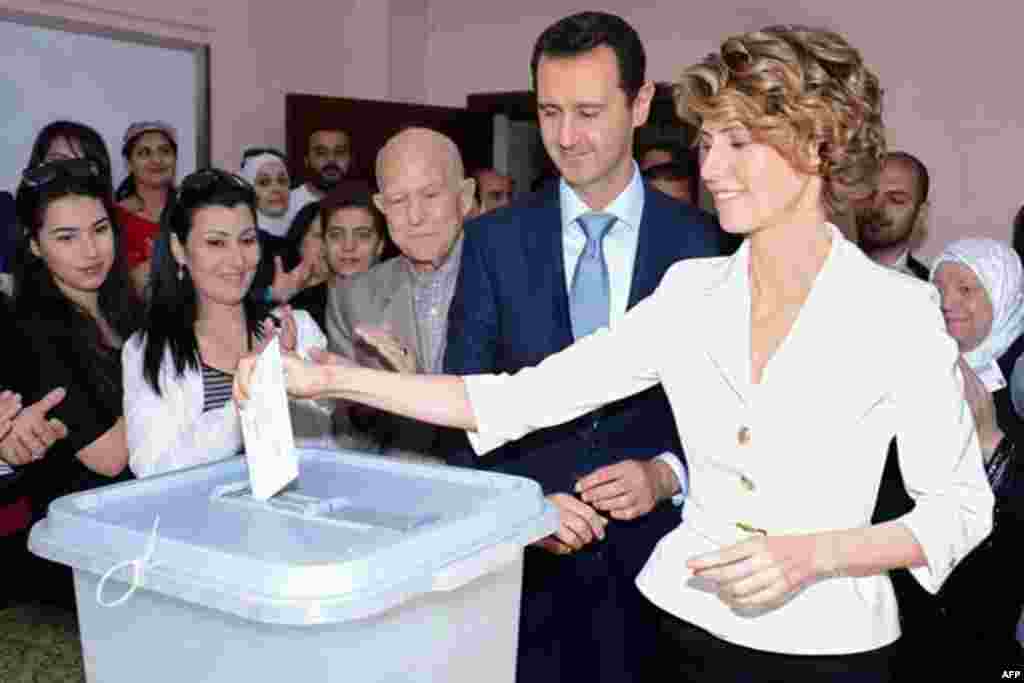 A photo from the official Facebook page of Syria&#39;s First Lady Asma al-Assad shows Syrian President Bashar al-Assad watches on as she votes at a polling station in Maliki, Damascus, June 3, 2014.