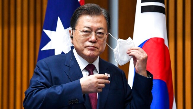 South Korean President Moon Jae-in removes his mask as he witnesses a signing ceremony at Parliament House, in Canberra, Australia, Dec. 13, 2021.