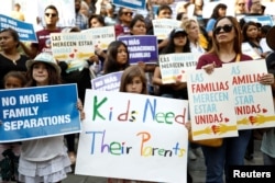 People hold signs to protest against U.S. President Donald Trump's executive order to detain children crossing the southern U.S. border and separating families outside of City Hall in Los Angeles, California, June 7, 2018.