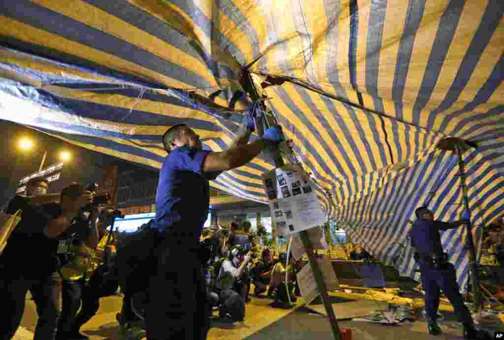 Riot police remove barricades after they moved into the area occupied by the pro-democracy protesters in the Mong Kok district of Hong Kong, early Friday, Oct. 17, 2014.