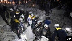 This photo provided on Jan. 7, 2018, by the Syrian Civil Defense White Helmets, which has been authenticated based on its contents and other AP reporting, shows Civil Defense workers inspecting a damaged building after a bombing in Idlib, Syria.