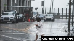 Seorang perempuan berjalan di tengah hujan lebat dan angin kencang yang dipicu badai Eta di Miami, Florida, 9 November 2020. (Foto:AFP)