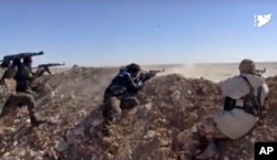 FILE - This frame grab from a video provided by the Syria Democratic Forces (SDF), shows fighters from the SDF opening fire on an Islamic State group's position, in Raqqa's eastern countryside, Syria, March 6, 2017.