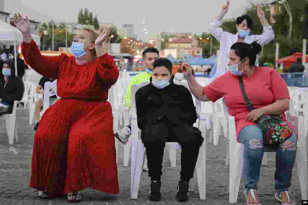 ႐ုိေမးနီးယားႏုိင္ငံ Bucharest ၿမိဳ႕မွာ ႏွာေခါင္းစည္းတပ္ၿပီး ဂီတေဖ်ာ္ေျဖပြဲ ၾကည့္႐ႈေနသူအခ်ဳိ႕။ (စက္တင္ဘာ ၁၈၊ ၂၀၂၀)