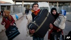 Des membres d'une famille syrienne portent leurs baggages après avoir passé la frontière de la Turquie près d'Hatay, dans le sud-est, le 18 décembre 2016.