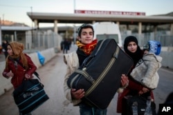 FILE - Members of a Syrian family carry their belongings after they crossed into Turkey at the Cilvegozu border gate with Syria, near Hatay, southeastern Turkey, Dec, 18, 2016.