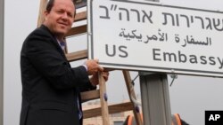 In this photo released by the Jerusalem Municipality, mayor Nir Barkat poses with a new road sign to the new U.S. Embassy in Jerusalem, Israel, May 7, 2018.