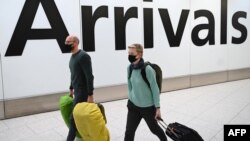 Passengers wear face masks as they arrive with their luugage at Terminal 4 of London Heathrow Airport in west London on January 28, 2020.