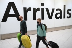 Passengers wear face masks as they arrive with their luugage at Terminal 4 of London Heathrow Airport in west London on January 28, 2020. - Chinese President Xi Jinping said Tuesday the country was waging a serious fight against the "demon" coronavirus ou