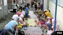 Anak-anak dan perempuan di tempat hunian sementara Dongkelsari berbuka puasa dengan menu sederhana teh manis dan nasi bungkus, Senin (29/8).