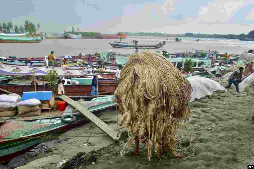 A worker carries jute to load onto a boat at a rural market in Munshigonj, Bangladesh.