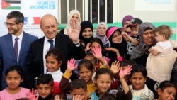 Le ministre des Affaires étrangères français Jean-Yves Le Drian (2e-G) avec des réfugiés syriens du camp d’Azraq participant au projet d'ONU Femmes "Oasis pour les femmes et les filles."