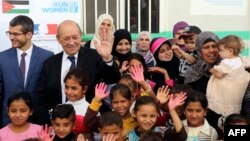 Le ministre des Affaires étrangères français Jean-Yves Le Drian (2e-G) avec des réfugiés syriens du camp d’Azraq participant au projet d'ONU Femmes "Oasis pour les femmes et les filles."