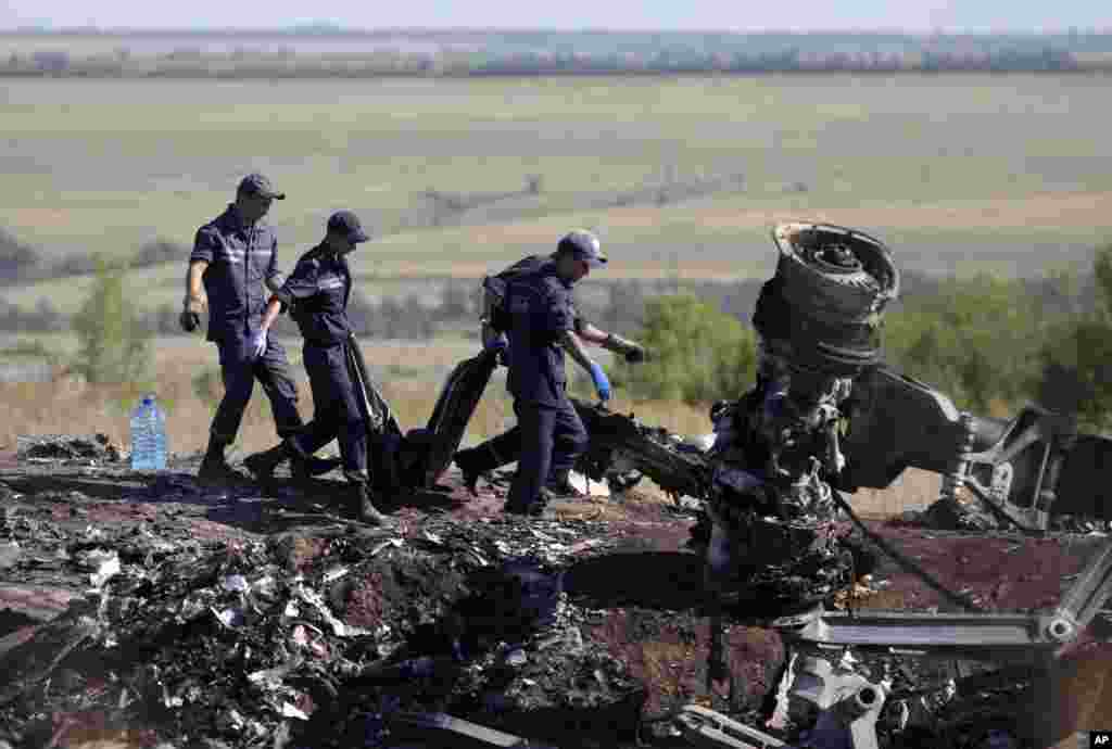 Emergency workers carry a victim's body in a plastic bag at the crash site of Malaysia Airlines Flight 17 near the village of Hrabove, Donetsk region, eastern Ukraine, July 21, 2014. 