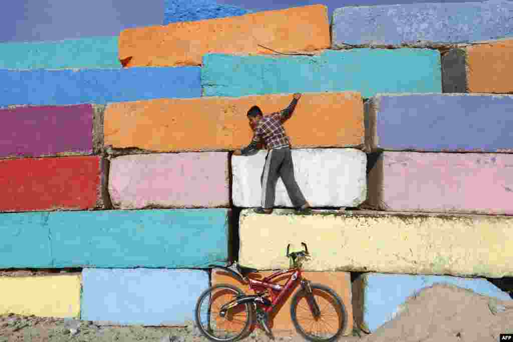 A Palestinian boy climbs a big stone wall, that was painted by local artists at the seaport in Gaza City in an attempt to bring more vibrant colors to the city.