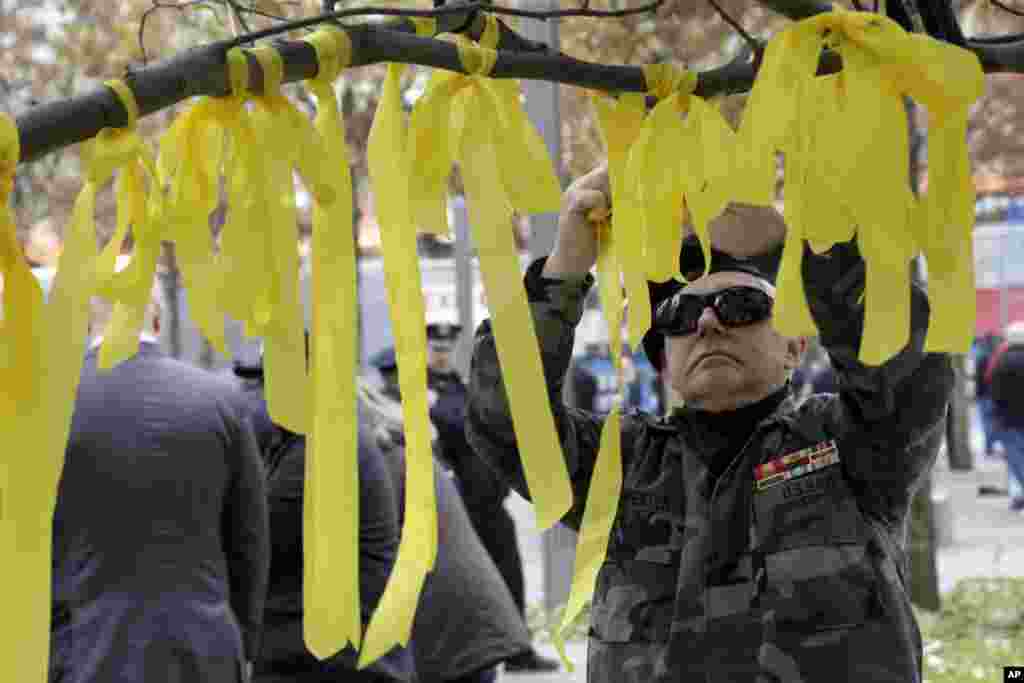 Kevin Carpenter, of Nassau County Chapter 82 of the Vietnam Veterans of America, ties a yellow ribbon to the tree that survived the terror attack, during the Veterans Day observance at the 9/11 Memorial, in New York, November 10, 2012. (AP)