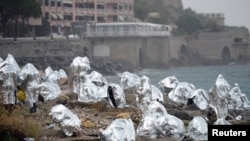 Un groupe de migrants se protègent dans des couverture de survie à la frontière entre la mer Méditerranée et Vintimille, Italie et Menton, France, le 14 juin 2015.