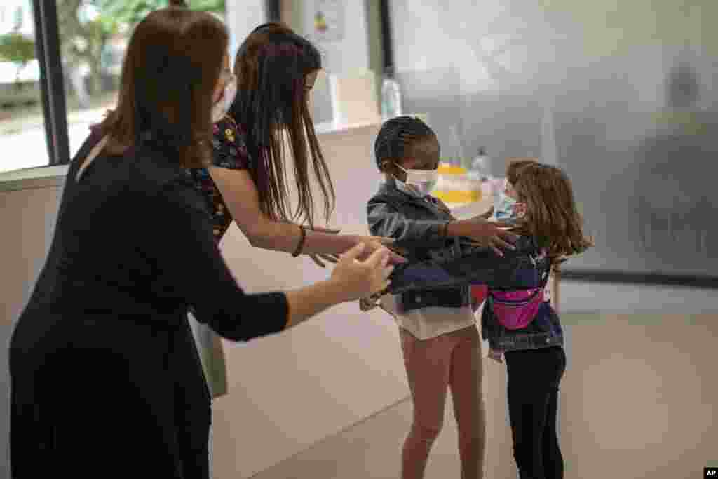 Teachers try to prevent the hug between Wendy Otin, 6, and Oumou Salam Niang, 6, as they meet on the first day of school after the lockdown, at a primary school in Barcelona, Spain.