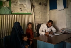 Dr. Gul Nazar writes a prescription for patients in the Mirbacha Kot hospital in Afghanistan, Oct. 25, 2021. The patients have to buy their own medicine as the hospital quickly runs out of medical supplies because of the country's crumbling economy.