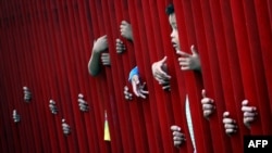 Tangan-tangan memegang pagar pabrik Gudang Garam, Kediri, Jawa Timur, menanti pembagian zakat. (Foto: Dok)