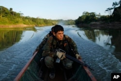 FILE - Counternarcotics police special forces cross a river on a boat after blowing a hole in a clandestine airstrip used by drug traffickers in Ciudad Constitucion, Peru, July 28, 2015.