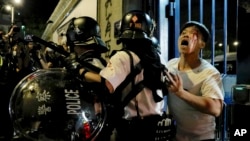 A bleeding man is taken away by policemen after attacked by protesters outside Kwai Chung police station in Hong Kong, Wednesday, July 31, 2019.