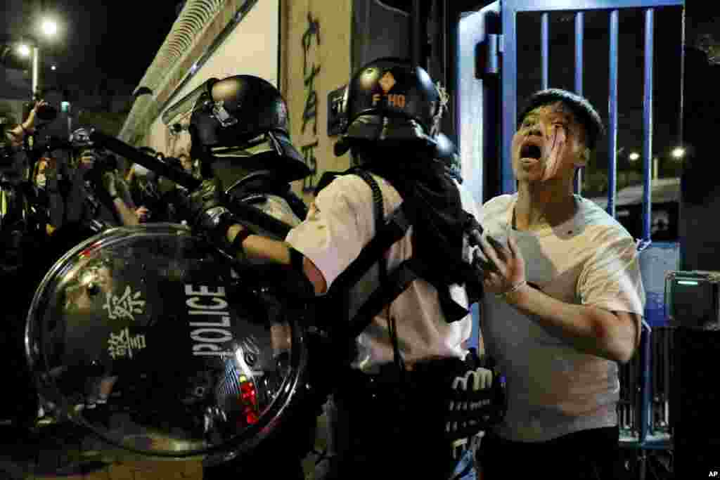 An injured man is taken away by policemen after attacked by protesters outside Kwai Chung police station in Hong Kong.