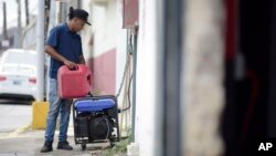 Juan Castro fills a generator with gasoline to power the cabinet building workshop where he is employed, in San Juan, Puerto Rico, April 18, 2018. Officials say it will take 24 to 36 hours to restore power after a blackout hit the entire island.