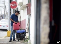 Juan Castro fills a power plant with gasoline to energize the cabinet building workshop where he works, in San Juan, Puerto Rico, April 18, 2018.