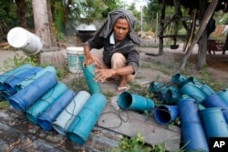 FILE - Cambodian farmer Suon Yom, 45, clears tubes before loading them with palm juice at Prey Pong-Ro village near Phnom Penh, Cambodia, Jan. 2, 2015.