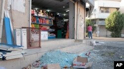 U homme nettoie les dégâts laisses devant sa boutique après une fusillade à al-Awamiya, Arabie Saoudite, 20 décembre 2014.