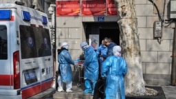 身穿防护服的医务人员把一名新冠病毒疑似感染的病人从武汉市一座居民楼里抬出。（2020年1月30日）