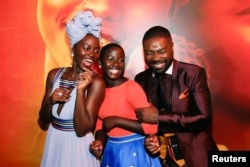 FILE - Actors Lupita Nyong'o (L), Madina Nalwanga (C) and David Oyelowo laugh after posing in the same manner as they appear on the movie poster seen behind him during the Los Angeles premiere of "Queen of Katwe" in Hollywood, California, Sept. 20, 2016.