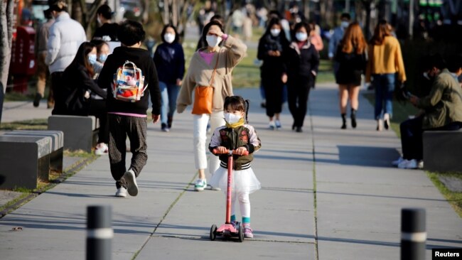 2020年4月3日戴着口罩的女孩在韩国首尔公园骑踏板车。