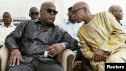 Felix Tshisekedi (L) talks to an unidentified visitor as he mourns the death of his father and veteran Congolese opposition leader Etienne Tshisekedi, in the courtyard of his residence in the Limete Municipality of the Democratic Republic of Congo's capital, Kinshasa, Feb. 3, 2017.