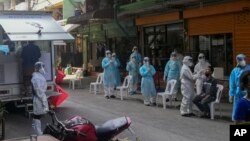 Petugas kesehatan mengenakan APD mengumpulkan sampel tes swab Covid-19 di Samut Sakhon, Bangkok Selatan, Thailand, Minggu, 20 Desember 2020.
