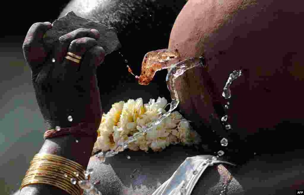 A relative uses a stone to break a pot of water carried by Sudhakar Reddy during his sister Swapna Reddy&#39;s funeral rites at a crematorium in Hyderabad, India. At least 14 people were killed, including Reddy, by twin bombings at a bustling shopping area of Hyderabad on Feb. 21, 2013.