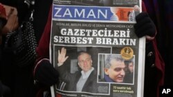 FILE - A copy of Zaman newspaper with a headline that reads "free journalists" is held during a protest against the detention of its editor-in-chief Ekrem Dumanli, Ankara, Dec. 17, 2014. 