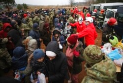 Belarusian Red Cross employees hand over humanitarian aid to migrants from the Middle East and elsewhere gathering at the Belarus-Poland border near Grodno, Belarus, Nov. 16, 2021.