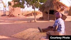 Women sit outside their huts on the outskirts of Harare, Zimbabwe. (S. Mhofu/VOA)