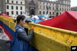 FILE - A woman writes a message to support a peace deal between the Colombian government and rebels of the Revolutionary Armed Forces of Colombia, FARC, at the main square in Bogota, Colombia, Oct. 8, 2016.