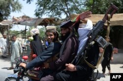 FILE - Afghan Taliban militants ride a motorbike as they took to the street to celebrate the cease-fire on the second day of Eid in the outskirts of Jalalabad, June 16, 2018.