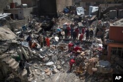 Civil protection rescue team work on the debris of a destroyed house to recover the bodies of people killed on the western side of Mosul, Iraq, March 24, 2017.