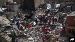 民防救援队员在摩苏尔西部被摧毁的建筑废墟内寻找尸体。（2017年3月24日）