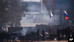 Aktivis-aktivis pro-Rusia terlihat di belakang barikade dengan bendera-bendera Rusia di depan kantor pemerintah Ukraina di Luhansk (8/4). (AP/Igor Golovniov)