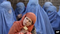 An Afghan girl waits with a group of women for food distribution by a German humanitarian organization in downtown Kunduz, Afghanistan, Dec.14, 2010.