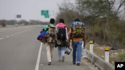 FILE - Venezuelan migrants walk to Lima along the shoulder of the Pan-American Highway near Tumbes, Peru, Aug. 26, 2018. 